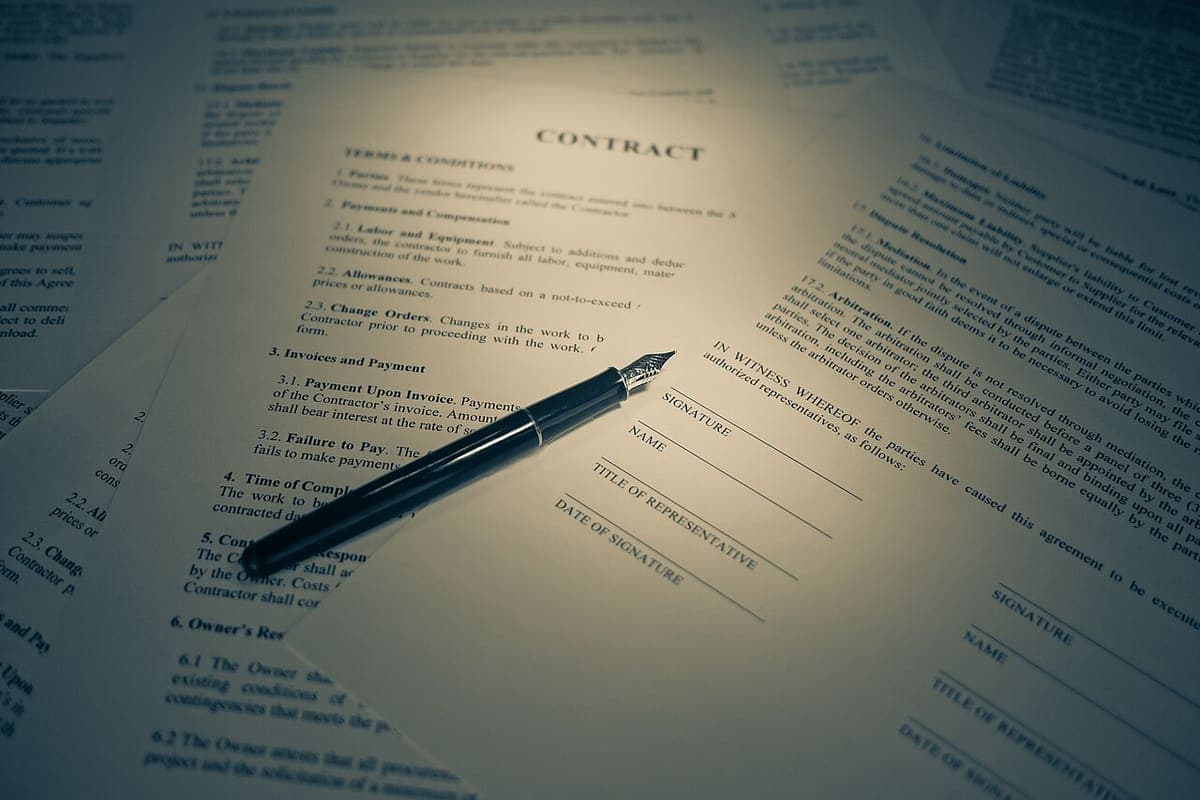 A printed agreement on a desk with a pen resting on it